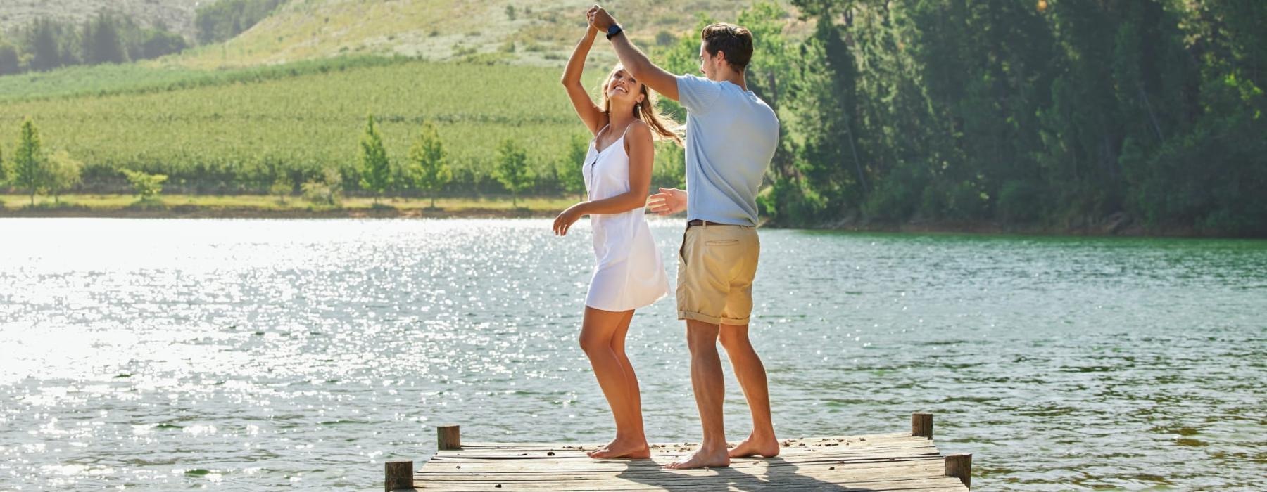 a man and woman standing on a dock by a lake